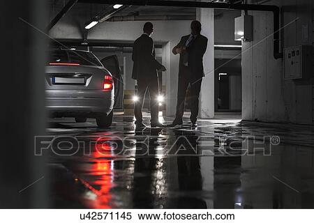 Full length of businessmen conducting suspicious business in parking lot View Large Photo Image Stock Photography - Full length of businessmen conducting suspicious business in parking lot. Fotosearch