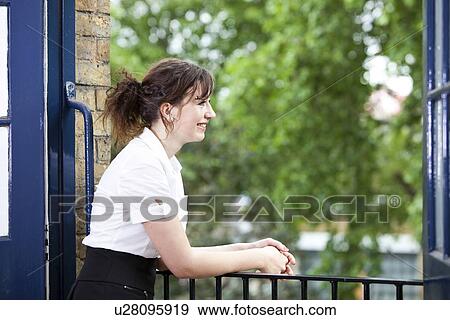 Happy young businesswoman leaning on railing while looking away View Large Photo Image Stock Photo - Happy young businesswoman leaning on railing while looking away. Fotosearch