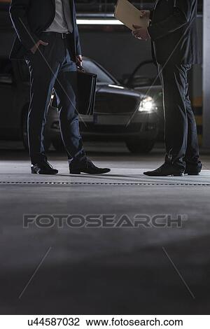 Stock Image - Low section of businessmen conducting suspicious business in basement. Fotosearch
