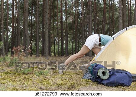 Stock Photo - Low section of woman entering tent in forest. Fotosearch
