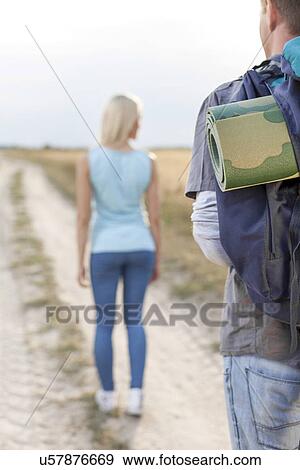 Male hiker carrying backpack with woman walking in foreground on field View Large Photo Image Stock Photo - Male hiker carrying backpack with woman walking in foreground on field. Fotosearch
