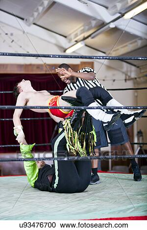 Stock Image - Man lifting rival while wrestling in ring. Fotosearch