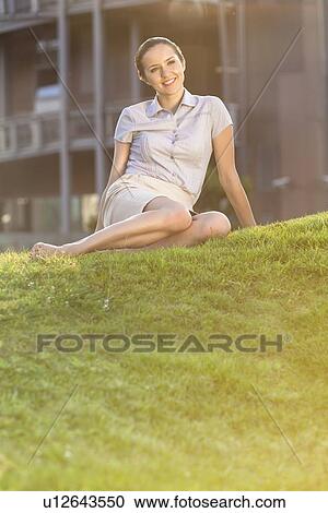 Smiling young businesswoman relaxing in office lawn View Large Photo Image Stock Image - Smiling young businesswoman relaxing in office lawn. Fotosearch