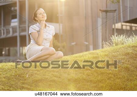 Thoughtful young businesswoman relaxing in office lawn View Large Photo Image Picture - Thoughtful young businesswoman relaxing in office lawn. Fotosearch