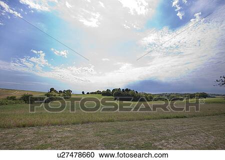View of grassy land against cloudy sky View Large Photo Image Stock Image - View of grassy land against cloudy sky. Fotosearch