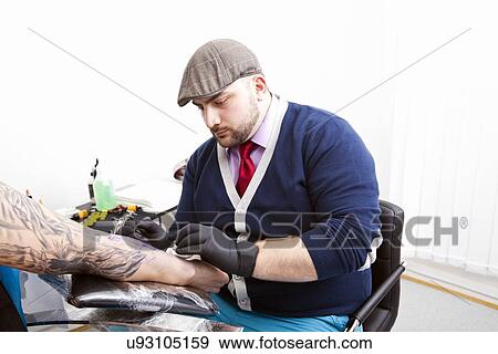 Young artist tattooing man's arm in tattoo parlor View Large Photo Image Stock Photo - Young artist tattooing man's arm in tattoo parlor. Fotosearch