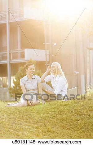 Young businesswomen gossiping in office lawn View Large Photo Image Stock Photo - Young businesswomen gossiping in office lawn. Fotosearch