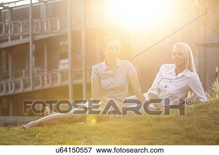Young businesswomen relaxing on office lawn View Large Photo Image Stock Photo - Young businesswomen relaxing on office lawn. Fotosearch