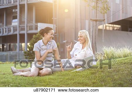 Young businesswomen spending leisure time on office lawn View Large Photo Image Stock Image - Young businesswomen spending leisure time on office lawn. Fotosearch