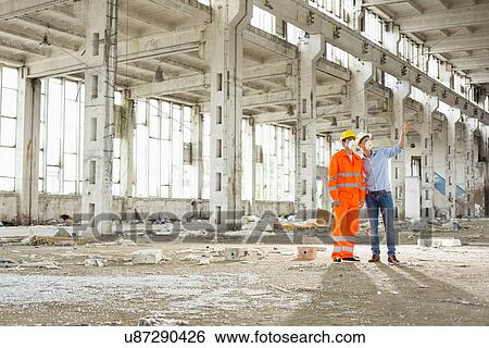 Full length of construction workers in protective workwear discussing at construction site View Large Photo Image Stock Photograph - Full length of construction workers in protective workwear discussing at construction site. Fotosearch
