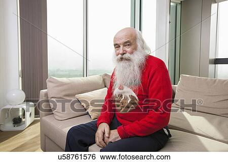 Stock Photograph - Portrait of senior man sitting on sofa bed. Fotosearch