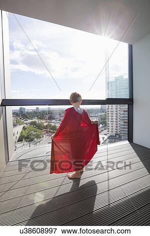 Stock Photo - Rear view of boy in superhero costume at home. Fotosearch