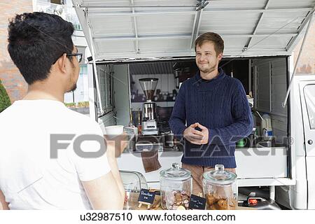 Stock Image - Vendor looking customer at mobile coffee shop. Fotosearch