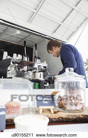Stock Image - Young man preparing coffee at mobile shop. Fotosearch
