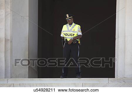 Stock Image - Black policeman walks in front of statue for Lincoln at the National Action to Realize the Dream march and rally commemorating the 50th Anniversary of the march on Washington, D. C.. Fotosearch