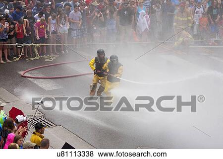 Stock Photo - Men dressed in yellow firemen slickers and firehoses have annual Waterfight on July 4, Ouray, CO. Fotosearch