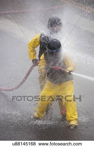 Stock Photo - Men dressed in yellow firemen slickers and firehoses have annual Waterfight on July 4, Ouray, CO. Fotosearch