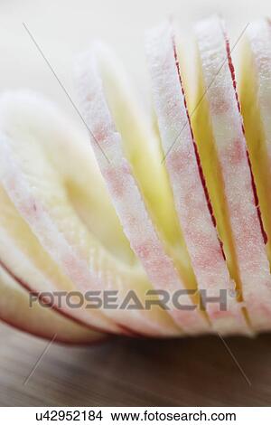 Picture - Peeled And Sliced Red Devil Apple On Wood. Fotosearch