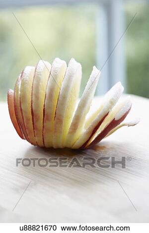 Stock Image - Peeled And Sliced Red Devil Apple On Wood. Fotosearch