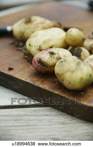 Stock Photo - Potatoes Waiting To Be Peeled On Chopping Board. Fotosearch
