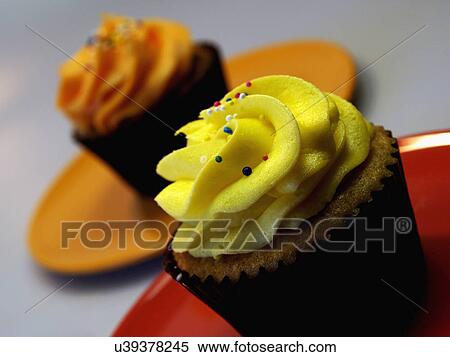 Two Iced Lemon And Orange Cupcakes On Red Plate View Large Photo Image Stock Photography - Two Iced Lemon And Orange Cupcakes On Red Plate. Fotosearch