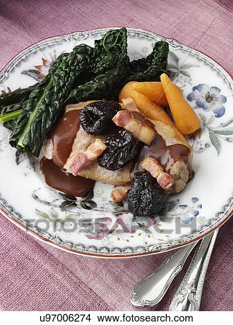 Picture - A plate of double pork chops with lardons prunes and cavolo nero. Fotosearch