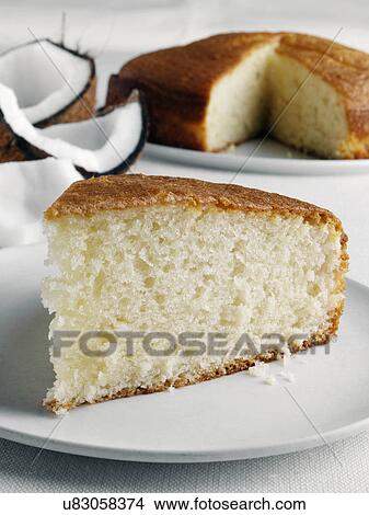 A slice of coconut cake with a whole cake and coconut pieces behind View Large Photo Image Picture - A slice of coconut cake with a whole cake and coconut pieces behind. Fotosearch
