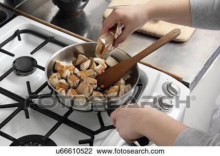 Stock Image - Adding spice to frying chicken. Fotosearch