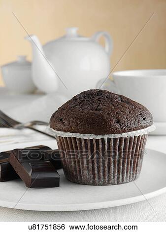 Stock Photograph - Breakfast chocolate muffin with chocolate pieces and tea set. Fotosearch