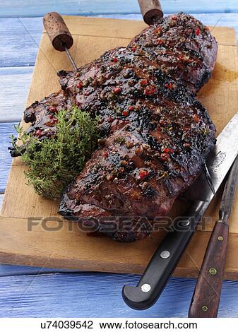 Stock Image - Butterflied leg of lamb marinaded and barbecued. Fotosearch