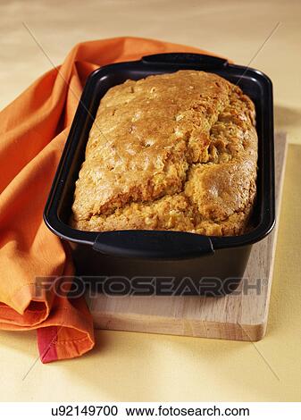 Stock Image - Cooked Cornbread Loaf In Tin On Wooden Board With Orange Napkin. Fotosearch