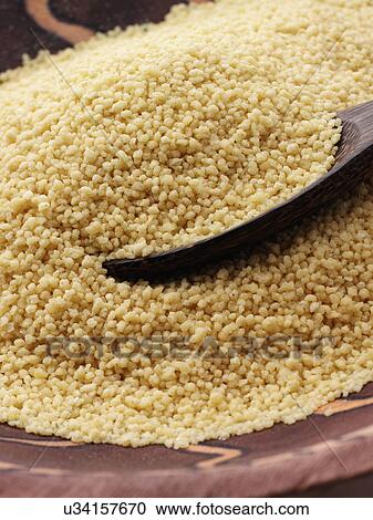 Stock Image - Couscous in an African wooden bowl. Fotosearch