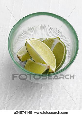 Stock Photography - Cut limes in a green glass bowl. Fotosearch