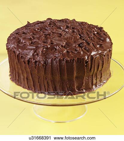 Stock Image - Devil'S Food Cake, Whole Chocolate Cake Covered With Chocolate Butter Cream Frosting, On Glass Serving Plate, Yellow Background. Fotosearch