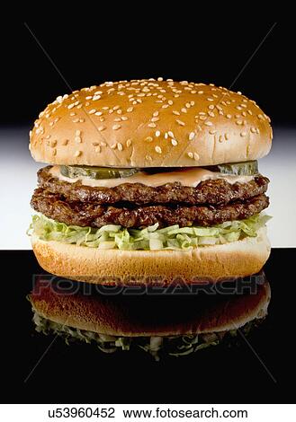 Stock Image - Double Hamburger In Seeded Bun On Black Tabletop. Fotosearch