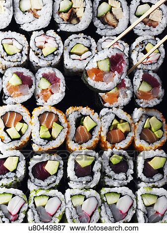 Stock Photo - Entire frame sushi overhead with chopsticks lifting a sushi. Fotosearch