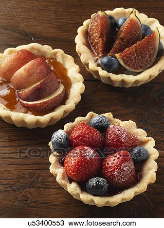 Stock Image - Fig tart, nectarine tart and berry tart on a wood background. Fotosearch