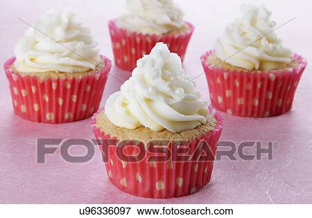 Stock Photo - Four Cupcakes In Pink And White Polka Dot Cases, Topped With Piped Buttercream And Decorated With Small Pearls, On Pink. Fotosearch