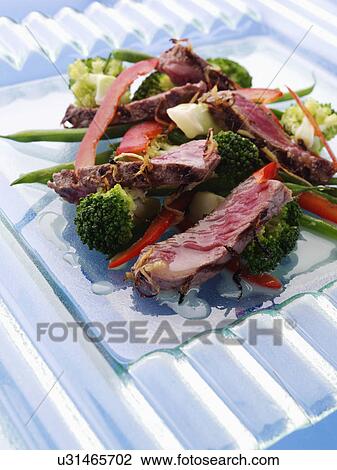 Stock Image - Griddled sirloin steak strips and vegetable salad. Fotosearch
