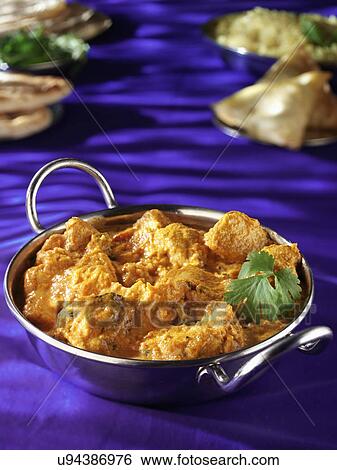 Stock Photograph - Metal Dish With Chicken Korma, Purple Tabletop With Naan Bread, Samosas And Rice. Fotosearch