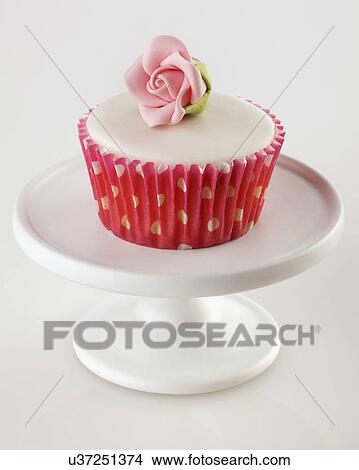 One Perfect White Iced Cupcake In Pink Polka Dot Cake Cases Decorated With Single Pink Sugar Craft Rose On White Cake Stand, White Tabletop View Large Photo Image Picture - One Perfect White Iced Cupcake In Pink Polka Dot Cake Cases Decorated With Single Pink Sugar Craft Rose On White Cake Stand, White Tabletop. Fotosearch