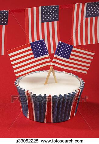 Stock Photography - One White Iced Cupcake Decorated With Two Small American Flags, On Red Background. Fotosearch