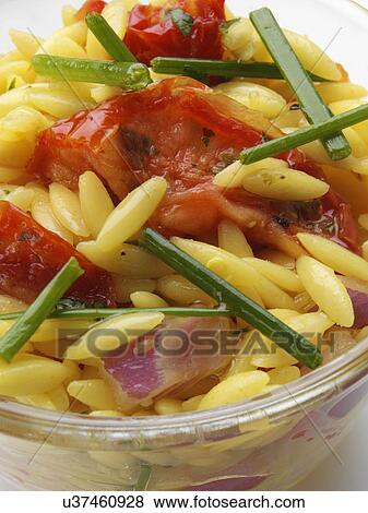 Stock Photo - Orzo rice sun dried tomato salad in glass bowl on a white background. Fotosearch