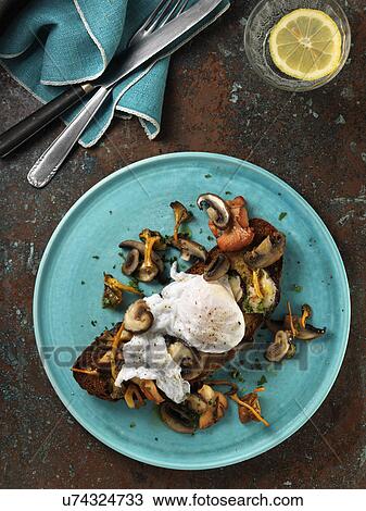 Stock Image - Poached duck egg on a bed of wild mushrooms on a slice of toasted San Francisco sourdough bread. Fotosearch