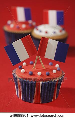 Stock Image - Red And White Iced Cupcakes With French Flags On Top, Red Background. Fotosearch