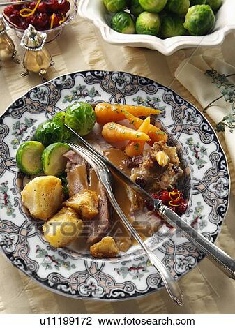 Stock Image - Roast turkey slices with stuffing Brussels sprouts baby carrots roast potatoes and gravy Christmas dinner. Fotosearch