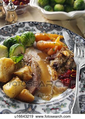 Stock Photo - Roast turkey slices with stuffing Brussels sprouts baby carrots roast potatoes and gravy Christmas dinner. Fotosearch