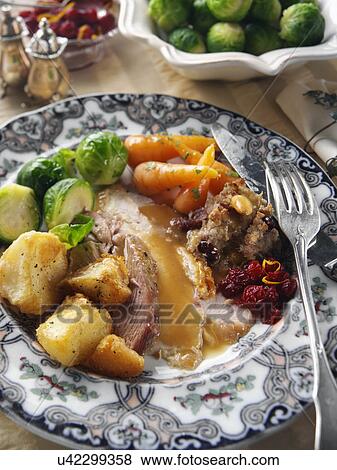 Stock Photo - Roast turkey slices with stuffing Brussels sprouts baby carrots roast potatoes and gravy Christmas dinner. Fotosearch