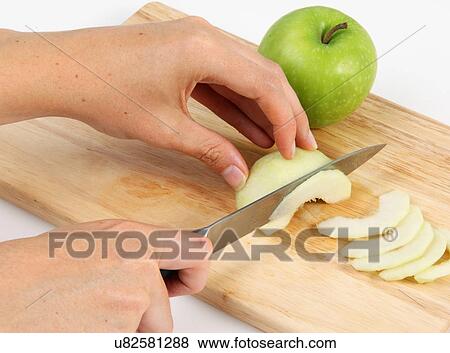 Stock Photo - Slicing A Green Apple On A Wooden Chopping Board. Fotosearch