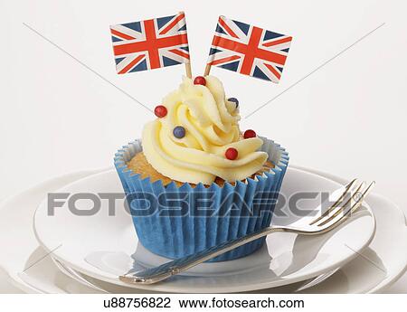 Themed British Celebration Cupcake, Blue Cake Case With Sponge Cupcake Topped With Buttercream With Red And Blue Sprinkles And Two Small Union Jack Flags, On White Plate With Pastry Fork View Large Photo Image Stock Image - Themed British Celebration Cupcake, Blue Cake Case With Sponge Cupcake Topped With Buttercream With Red And Blue Sprinkles And Two Small Union Jack Flags, On White Plate With Pastry Fork. Fotosearch